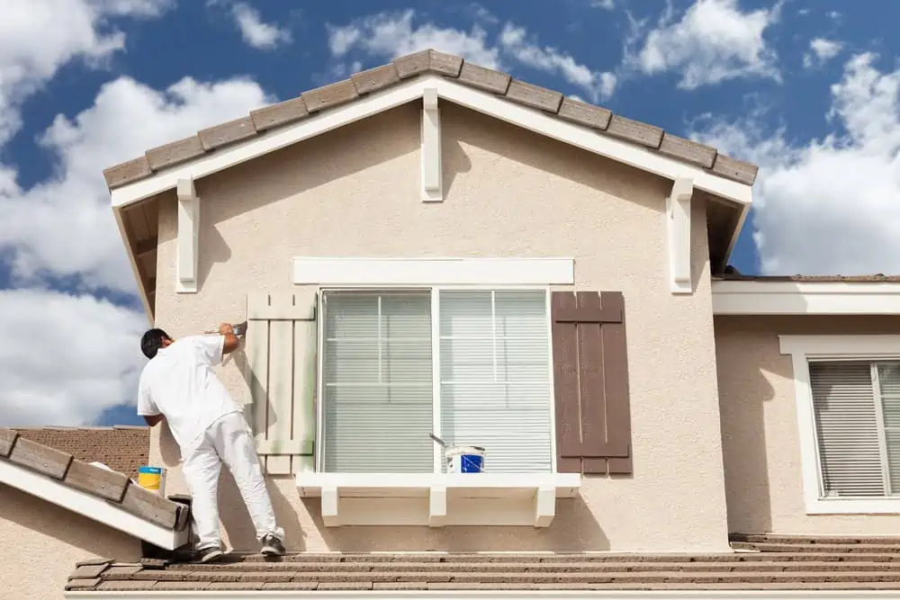 Man painting the two story house exterior