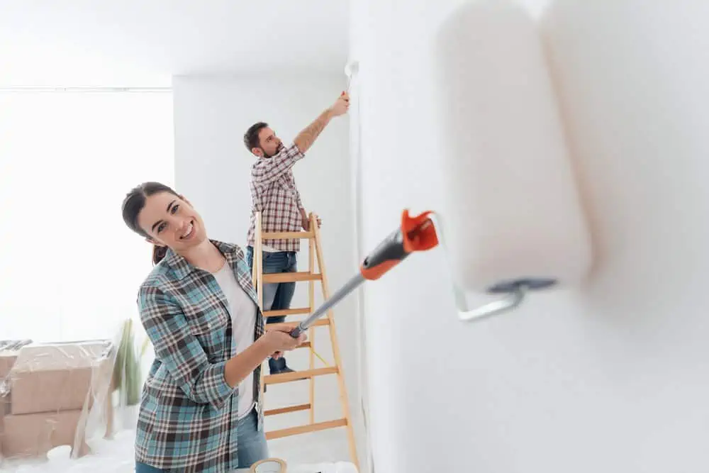 Couple painting their house interiors using paint rollers