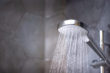 Modern shower head with running water in the bathroom
