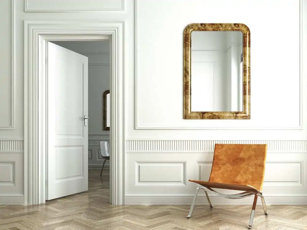 Classic mirror on classic white interior with chair and open door