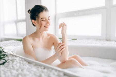 Pretty woman rubs her body with foam in the bathtub
