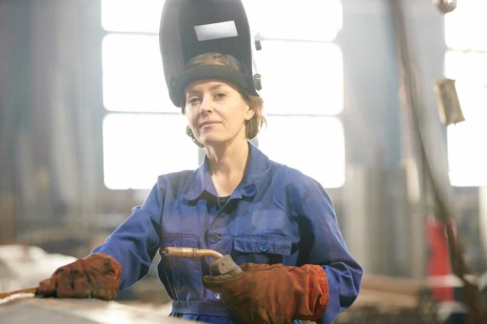 smiling female welder posing confidently while working