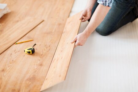 Carpenter hands installing wooden flooring