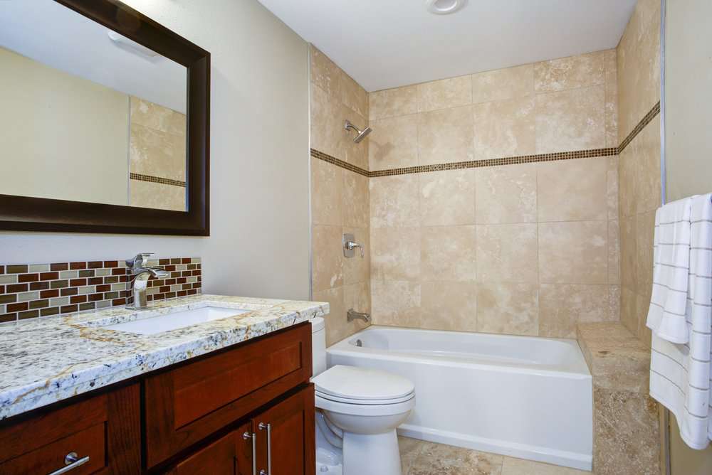 Bathroom with with bathtub and mahogany vanity and granite countertop 