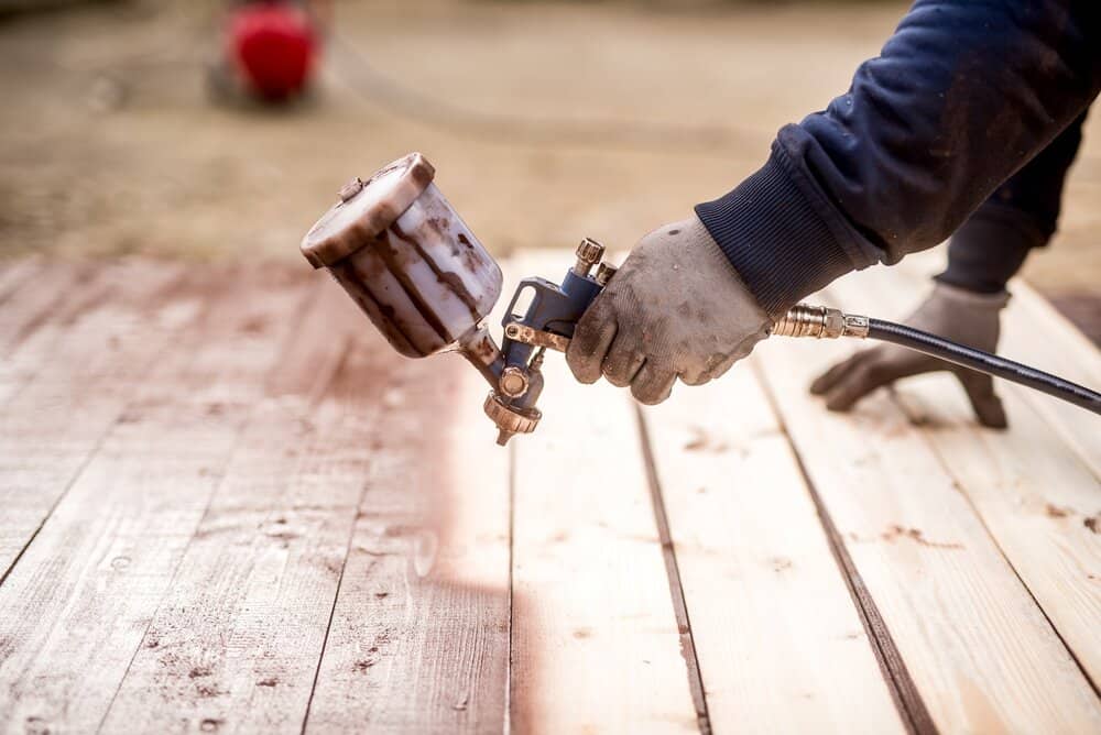 Worker hand using spray gun painting wood