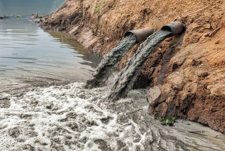 Dirty polluted water coming out of from tubes into the river