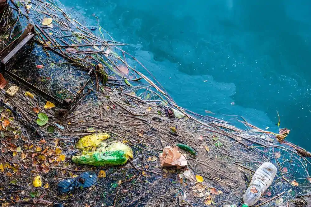 Water pollution old garbage and oil patches on river surface