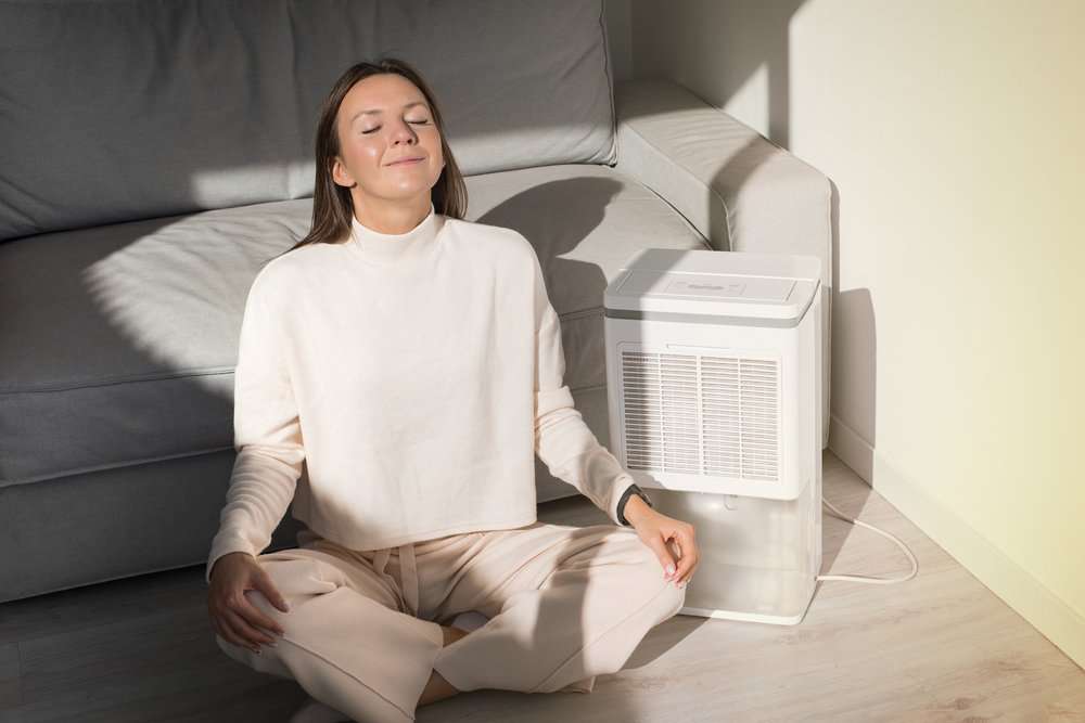 Woman sitting on the floor breathing fresh air at home