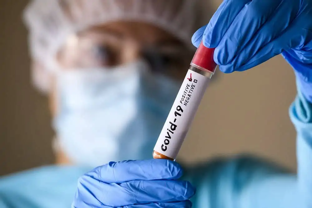 Woman in protective suit hold test tube with positive result infected with coronavirus
