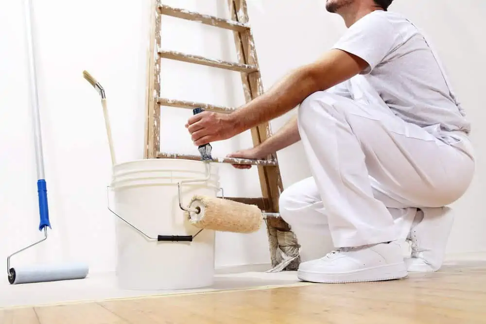 Painter man at work with roller bucket and scale