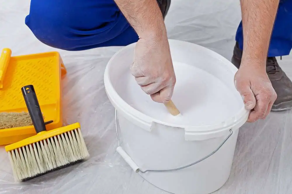 Worker hands stirring white paint