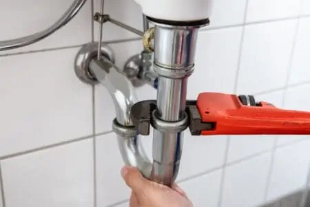 Plumber hand repairing sink with adjustable wrench
